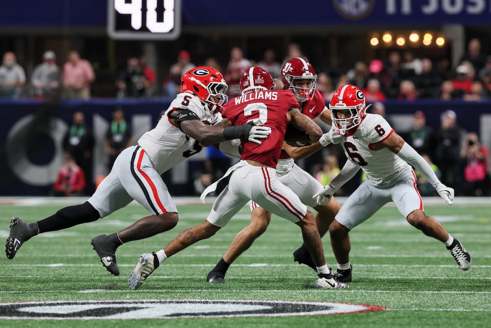 Alabama wide receiver Ryan Williams (center) is tackled by Georgia linebacker Raylen Wilson (left) and defensive back Daylen Everette during their SEC championship game at Mercedes-Benz Stadium on Saturday, Dec. 6, 2025, in Atlanta. (Jason Getz/AJC)