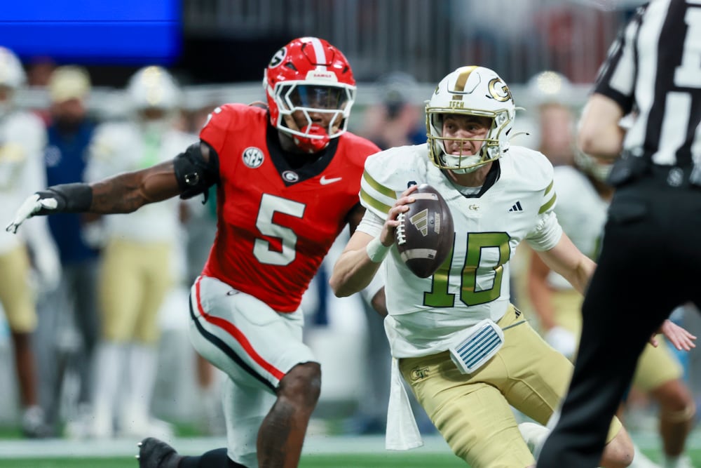 Georgia Tech quarterback Haynes King (right) is pressured by Georgia linebacker Raylen Wilson during their game at Mercedes-Benz Stadium on Friday, Nov. 28, 2025, in Atlanta. (Jason Getz/AJC)