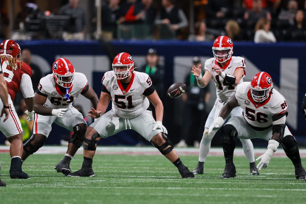 Georgia center Malachi Toliver snaps the ball to quarterback Gunner Stockton as offensive linemen Dontrell Glover (left) and Micah Morris (right) provide protection during their SEC championship game against Alabama at Mercedes-Benz Stadium on Saturday, Dec. 6, 2025, in Atlanta. (Jason Getz/AJC)