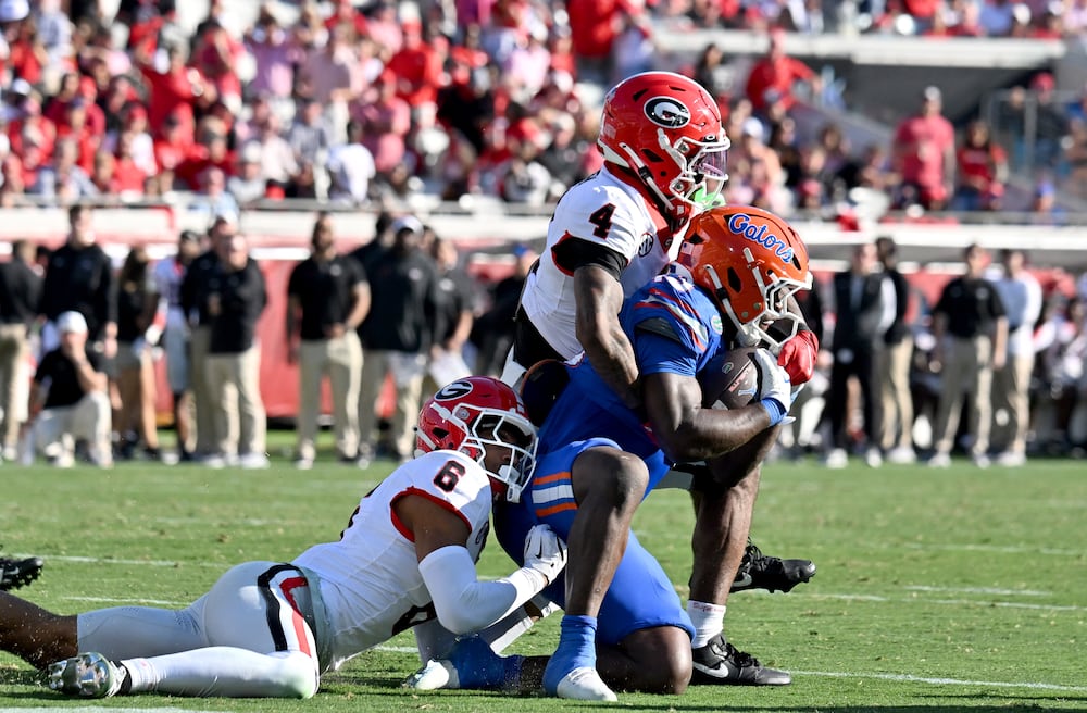Georgia defensive backs Daylen Everette (left) and KJ Bolden (top) tackle Florida running back Jadan Baugh in November in Jacksonville, Fla. (Hyosub Shin/AJC 2025)
