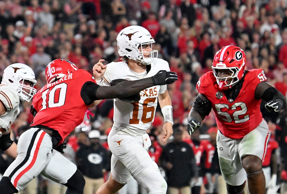 Texas quarterback Arch Manning (center) is hit by Georgia linebacker Zayden Walker (left), causing a fumble, at Sanford Stadium on Saturday, Nov. 15, 2025, in Athens. (Hyosub Shin/AJC)