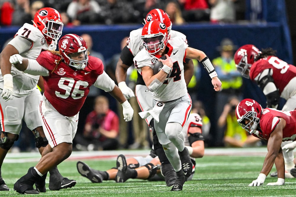 Georgia quarterback Gunner Stockton (center) runs a keeper play against Alabama defensive lineman Tim Keenan III (left) during their SEC championship game at Mercedes-Benz Stadium on Saturday, Dec. 6, 2025, in Atlanta. (Hyosub Shin/AJC)