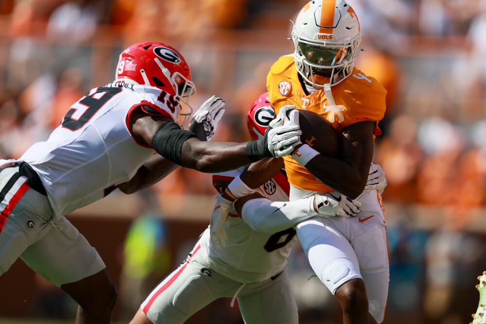 Tennessee wide receiver Mike Matthews (4) is tackled by Georgia linebacker Justin Williams (19) and Georgia defensive back Joenel Aguero (8) after a reception by Matthews during the first quarter at Neyland Stadium, Saturday, September 13, 2025, in Knoxville, Tenn. Georgia won 44-41 in overtime. Tennessee wide receiver Mike Matthews is an AJC Super 11 from Parkview high school. (Jason Getz / AJC)