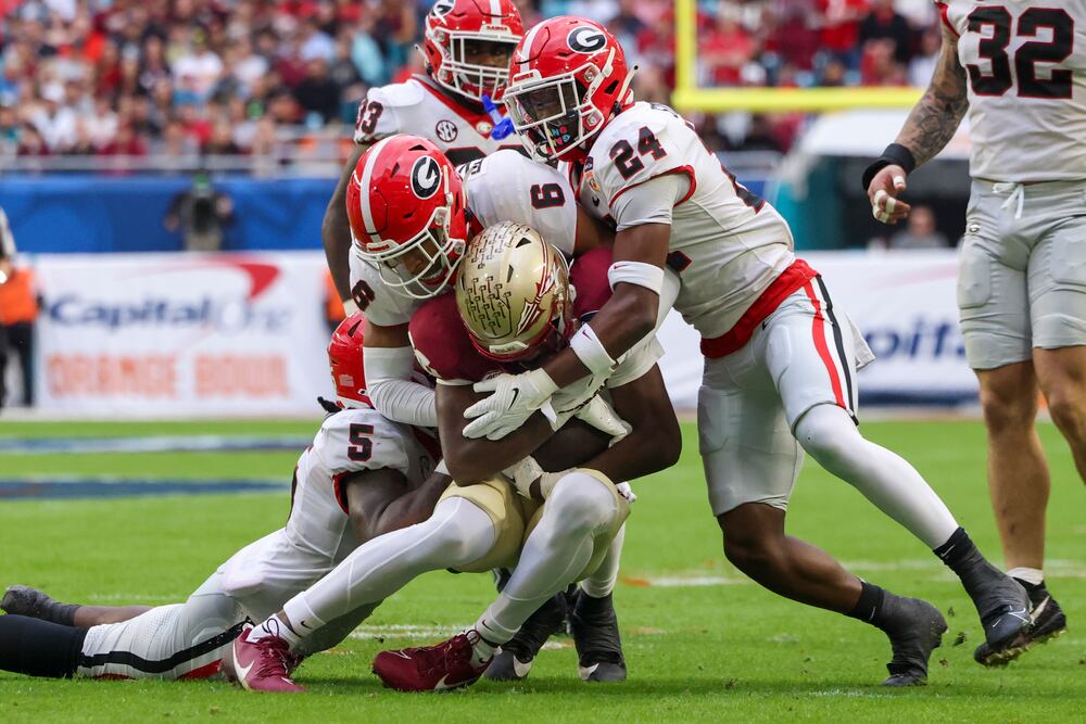 Florida State wide receiver Kentron Poitier (center) is tackled by Georgia linebacker Raylen Wilson (from left) and defensive backs Daylen Everette and Malaki Starks during the Orange Bowl at Hard Rock Stadium on Saturday, Dec. 30, 2023, in Miami Gardens, Fla. (Jason Getz/AJC)