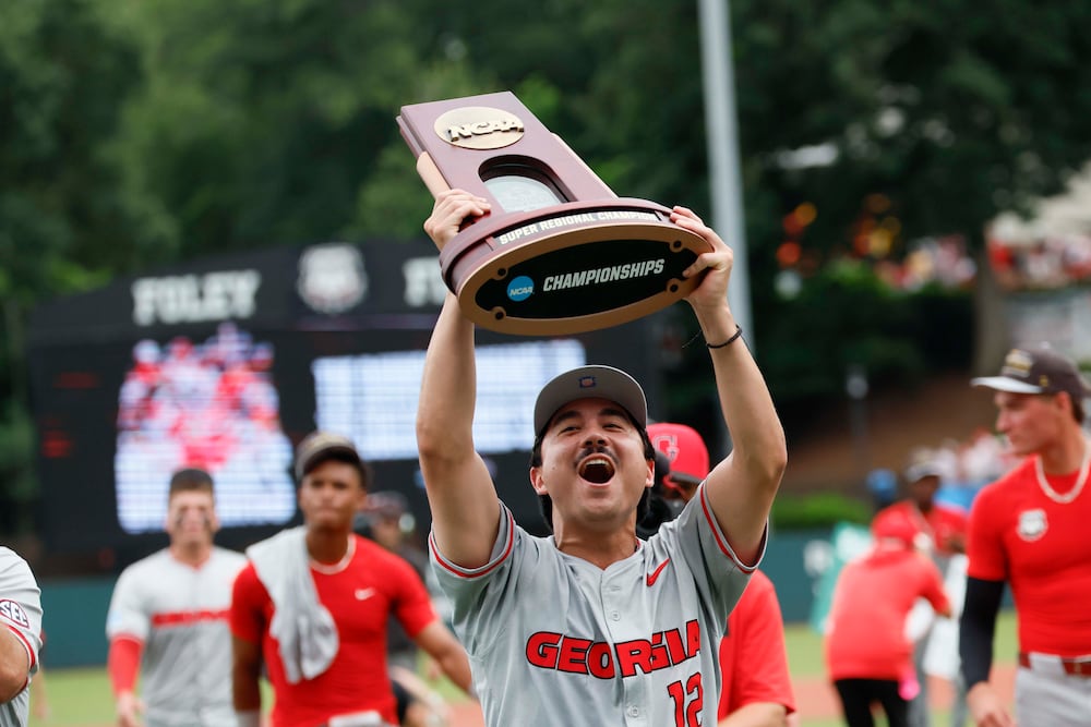 Georgia Bulldogs pitcher Caden Aoki (12) lifts the trophy as he celebrates with his team after winning the NCAA Super Regional series, defeating the Mississippi State Bulldogs 11-9 at Foley Field on Sunday, June 7, 2026, in Athens. Miguel Martinez/AJC)