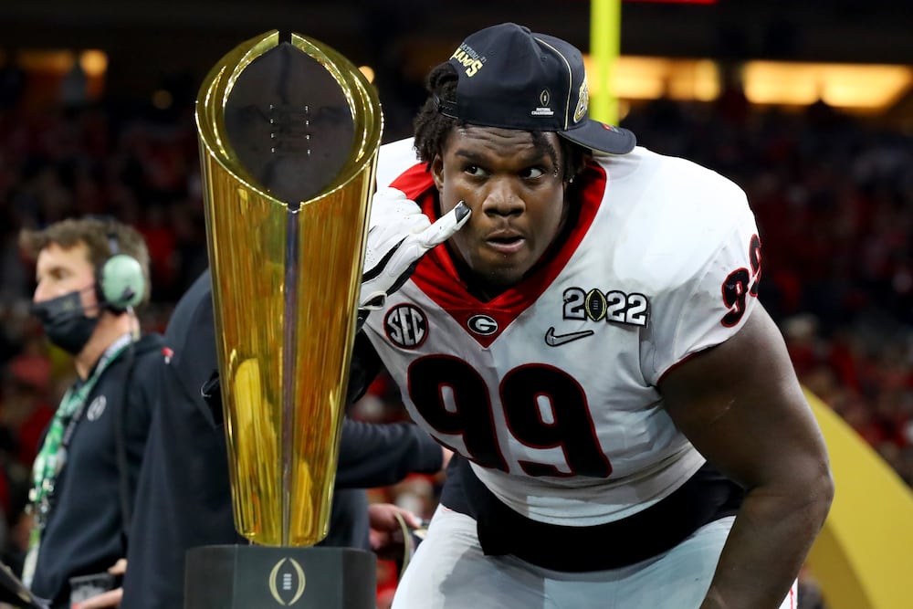 Georgia defensive lineman Jordan Davis checks out his reflection in the trophy after the Bulldogs 33-18 win against the Alabama Crimson Tide during their 2022 College Football Playoff national championship game on Monday, Jan. 10, 2022, at Lucas Oil Stadium in Indianapolis. (Curtis Compton/AJC)