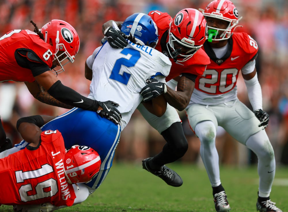 Kentucky running back Dante Dowdell (center) is tackled for a short gain by Georgia defensive back Joenel Aguero (left), linebacker Justin Williams (bottom) and defensive back Ellis Robinson IV at Sanford Stadium on Saturday, Oct. 4, 2025, in Athens. (Jason Getz/AJC)