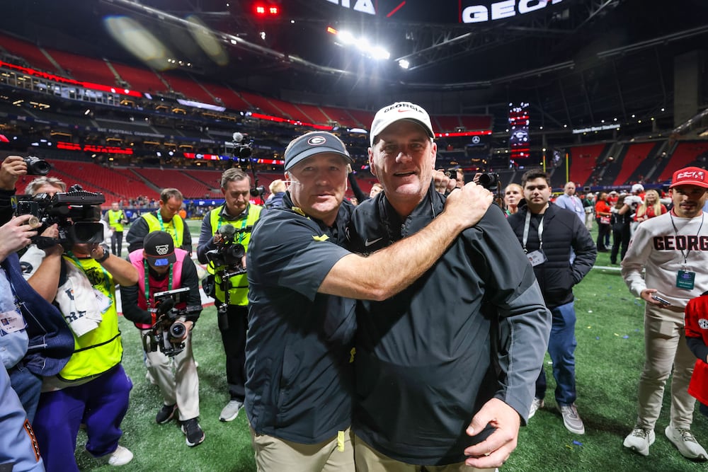 Georgia head coach Kirby Smart (left) and offensive coordinator Mike Bobo celebrate their 28-7 victory over Alabama in the SEC championship game at Mercedes-Benz Stadium on Saturday, Dec. 6, 2025, in Atlanta. (Jason Getz/AJC)