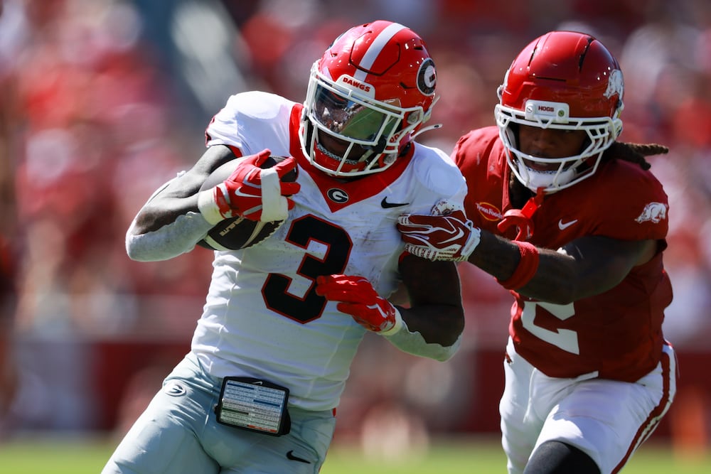 Georgia running back Nate Frazier (left) runs for a first down against Arkansas defensive back Shelton Lewis during their game at Donald W. Reynolds Razorback Stadium on Saturday, Sept. 19, 2026, in Fayetteville, Ark. (Jason Getz/AJC)