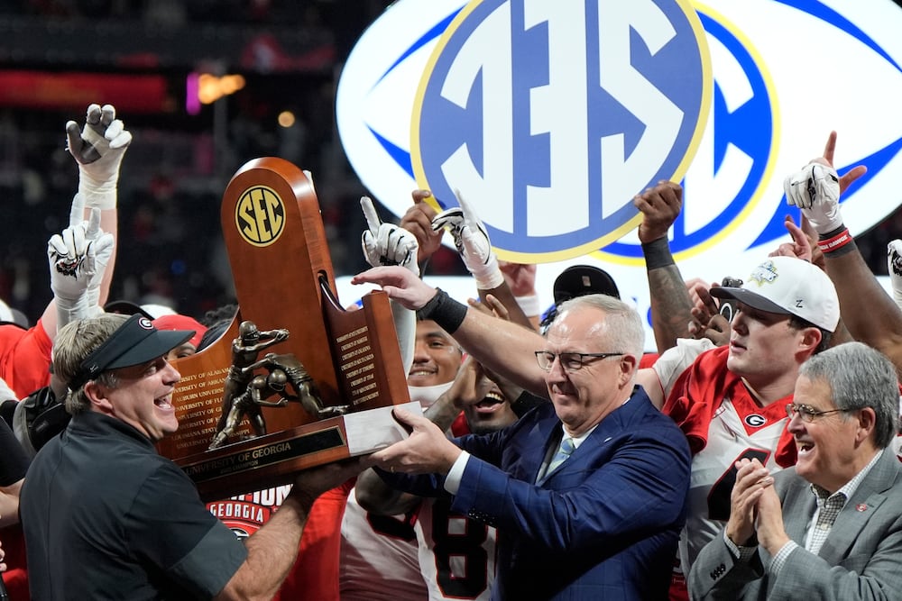 Georgia head coach Kirby Smart is handed the SEC trophy by Commissioner Greg Sankey as the team celebrates its win over Alabama in the 2025 SEC championship game. (Mike Stewart/AP)