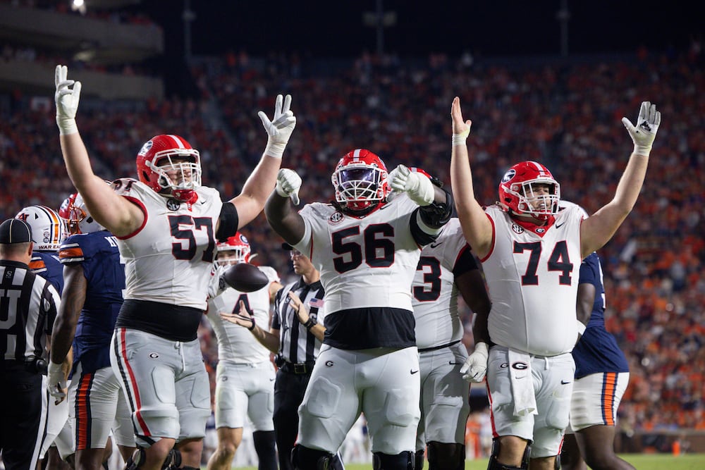 Georgia offensive lineman Monroe Freeling (from left), Micah Morris and Drew Bobo celebrate after running back Chauncey Bowens (not pictured) scores a touchdown against Auburn at Jordan-Hare Stadium on Saturday, Oct. 11, 2025, in Auburn, Ala. (Jason Getz/AJC)