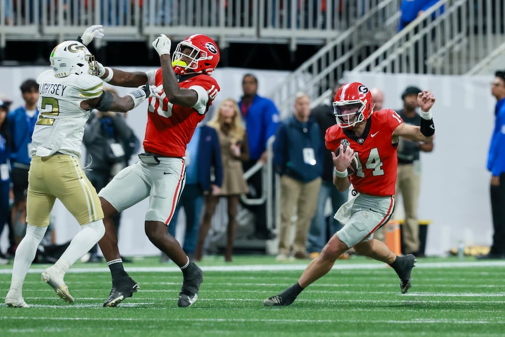 Georgia quarterback Gunner Stockton (right) runs for yards as tight end Elyiss Williams blocks Georgia Tech linebacker E.J. Lightsey at Mercedes-Benz Stadium on Friday, Nov. 28, 2025, in Atlanta. (Jason Getz/AJC)