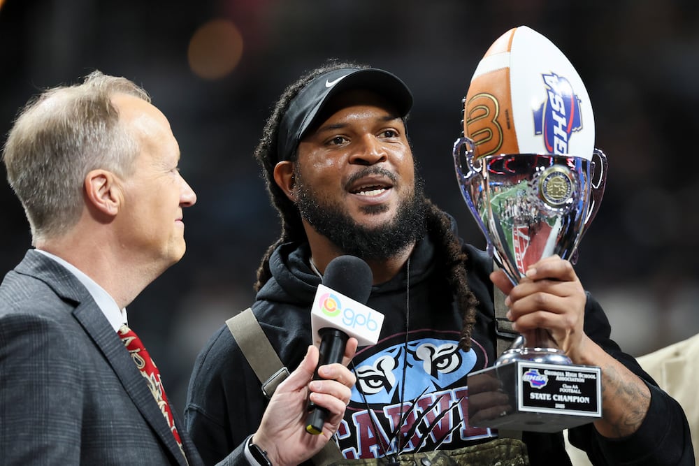 Carver-Columbus head coach Jarvis Jones celebrates with the trophy after their 24-7 win against Hapeville Charter in the Class 2A GHSA football championship at Mercedes-Benz Stadium, Tuesday, Dec. 16, 2025, in Atlanta. (Jason Getz/AJC)